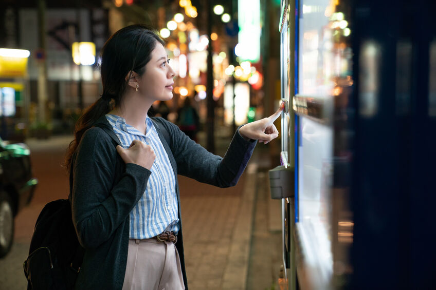 Woman standing at a vending machine looking at the options