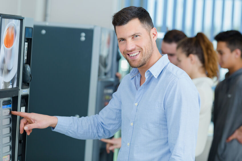 Businessman getting coffee from a vending machine